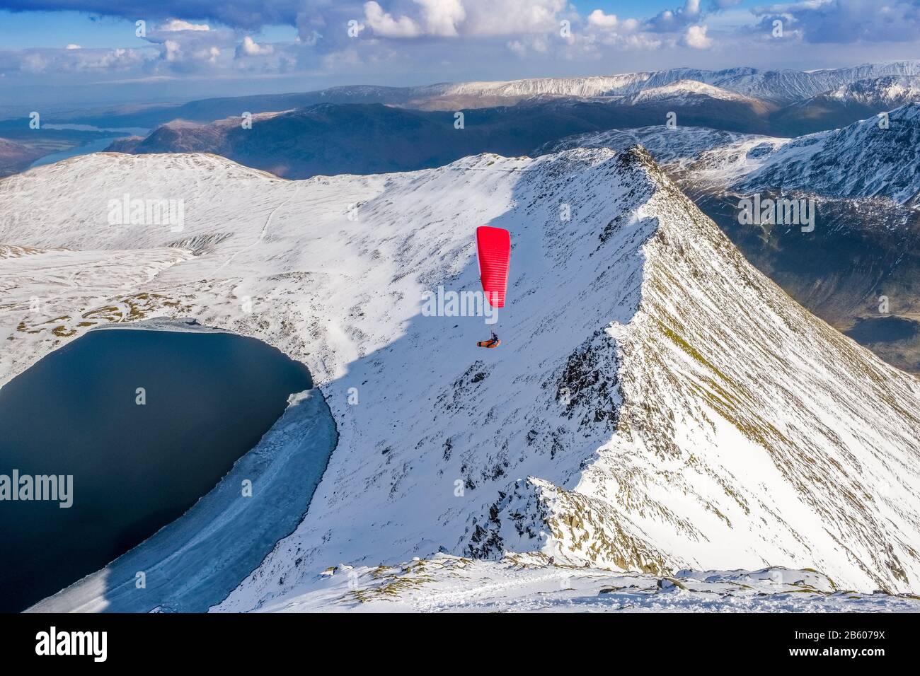 Ein Gleitschirmflieger, der im Winter über Die Streifkante auf Helvellyn fliegt. Lake District National Park, Cumbria, Großbritannien Stockfoto