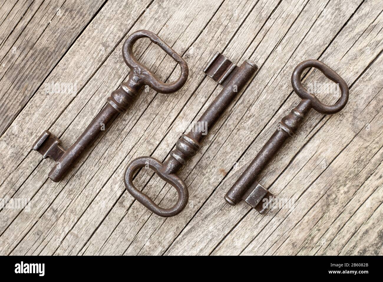 Drei parallele Vintage-Bügelschlüssel auf altem rustikalem Holzhintergrund, Fluchtraumkonzept Stockfoto