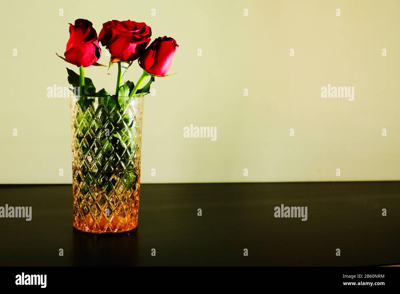 Drei rote Rosen in Glasvase auf weißem Hintergrund Stockfoto