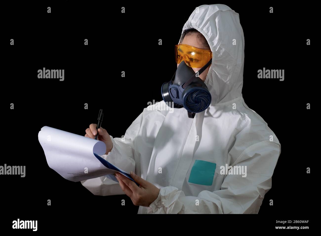 Frau hält Berichtsordner in weißer chemischer Schutzkleidung und Gasmaske mit gelber Brille am weißen Hintergrund, Wissenschaftlerin im Safet Stockfoto