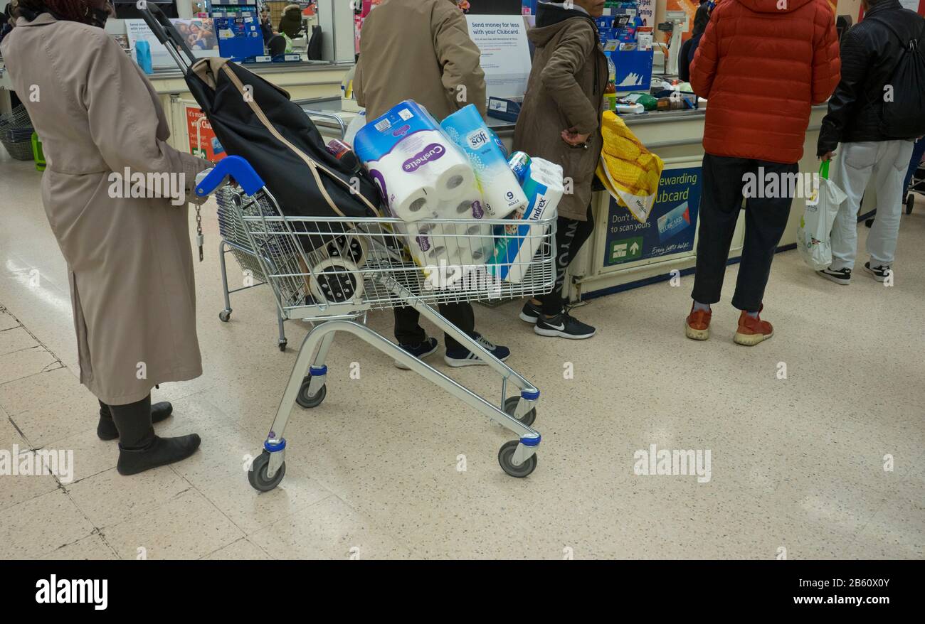 Kunden horten toilettenpapier und Grundwaren aufgrund der Coronavirus Epidemie in einem Tesco Supermarkt in London, England, Großbritannien Stockfoto