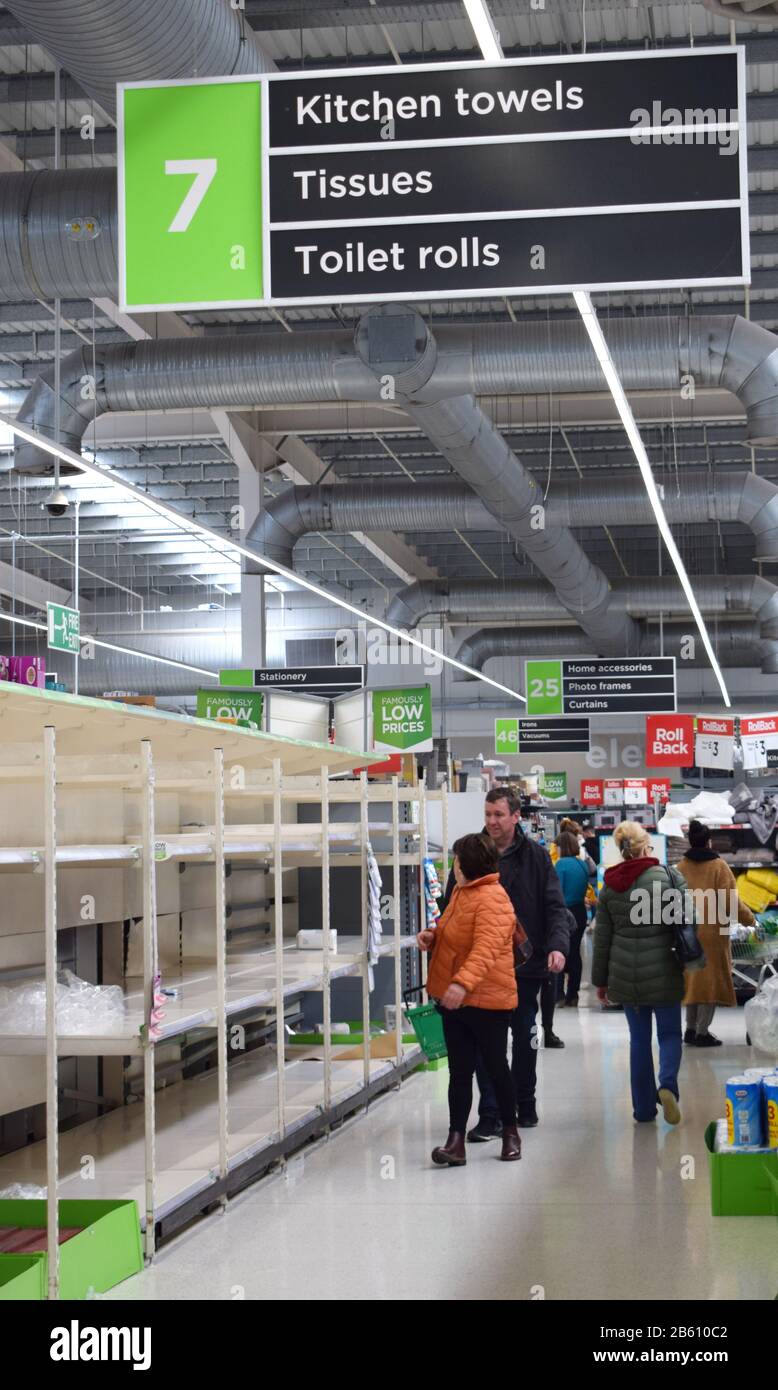 Britische Supermarktregale in der toilettenwalze/dem Papiergang des Ladens leer, während Menschen wegen Coronavirus in Panik einkaufen und Grundausstattung vorrätigen Stockfoto