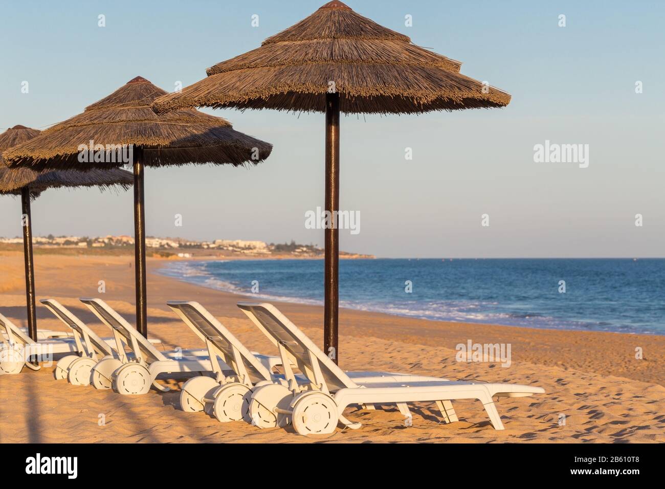 Sonnenliegen und Sonnenschirme für Touristen. Der portugiesische Strand an der Algarve. Stockfoto