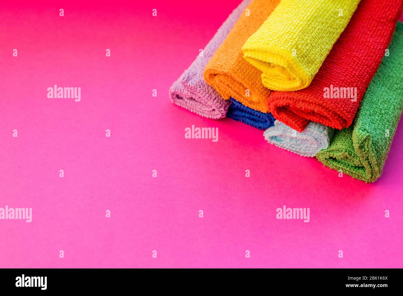 Bunte Mikrofaser-Reinigungstücher auf rosa Hintergrund gestapelt. Bunte, trockene Mikrofasertücher für die Reinigung verschiedener Oberflächen in Küche, Bad Stockfoto
