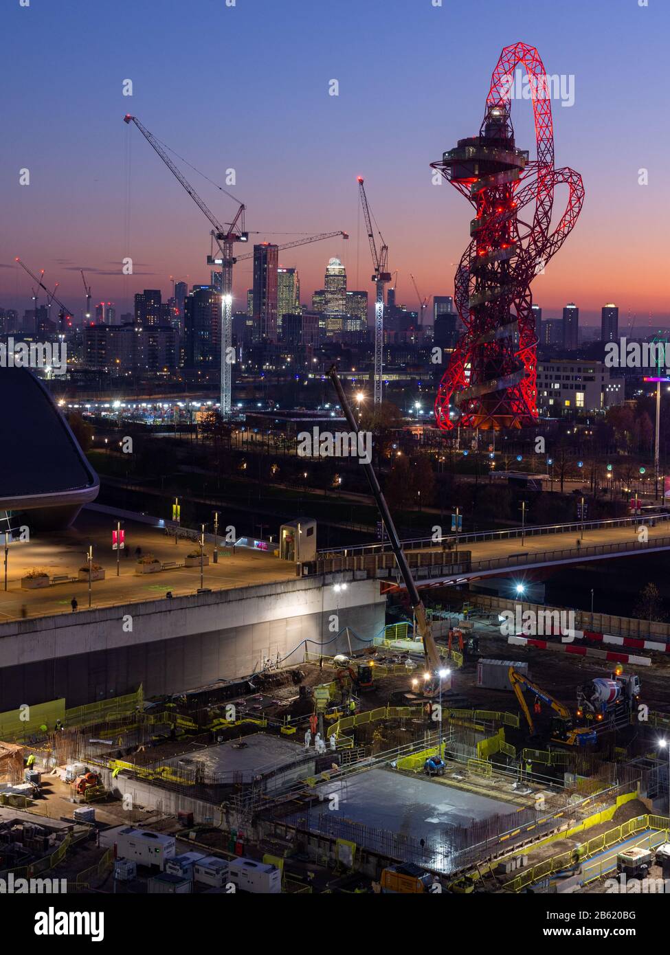 London, England, Großbritannien - 4. Dezember 2019: Hinter dem ArcelorMittal Orbit Tower und Wolkenkratzern des Docklands Finanzdistrikts in East Lon geht die Sonne unter Stockfoto