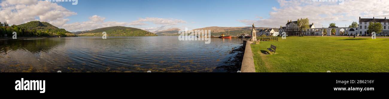 Inveraray, Schottland, Großbritannien - 13. Mai 2016: Sonne scheint auf die Häuser von Inveraray am Ufer von Loch Fyne, mit den Bergen der schottischen Highlands Stockfoto