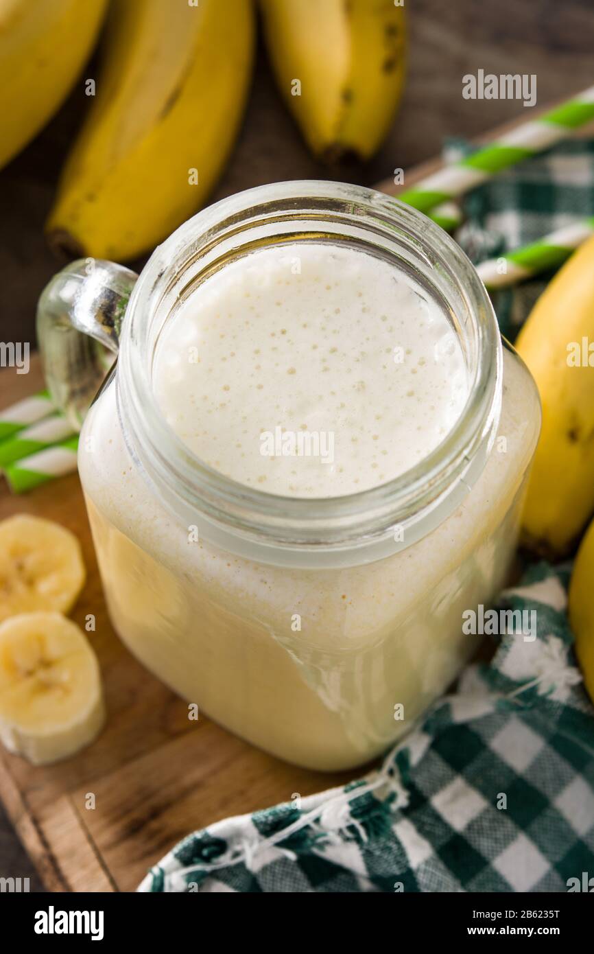Bananen-Smoothie im Mixbecher auf Holztisch Stockfoto