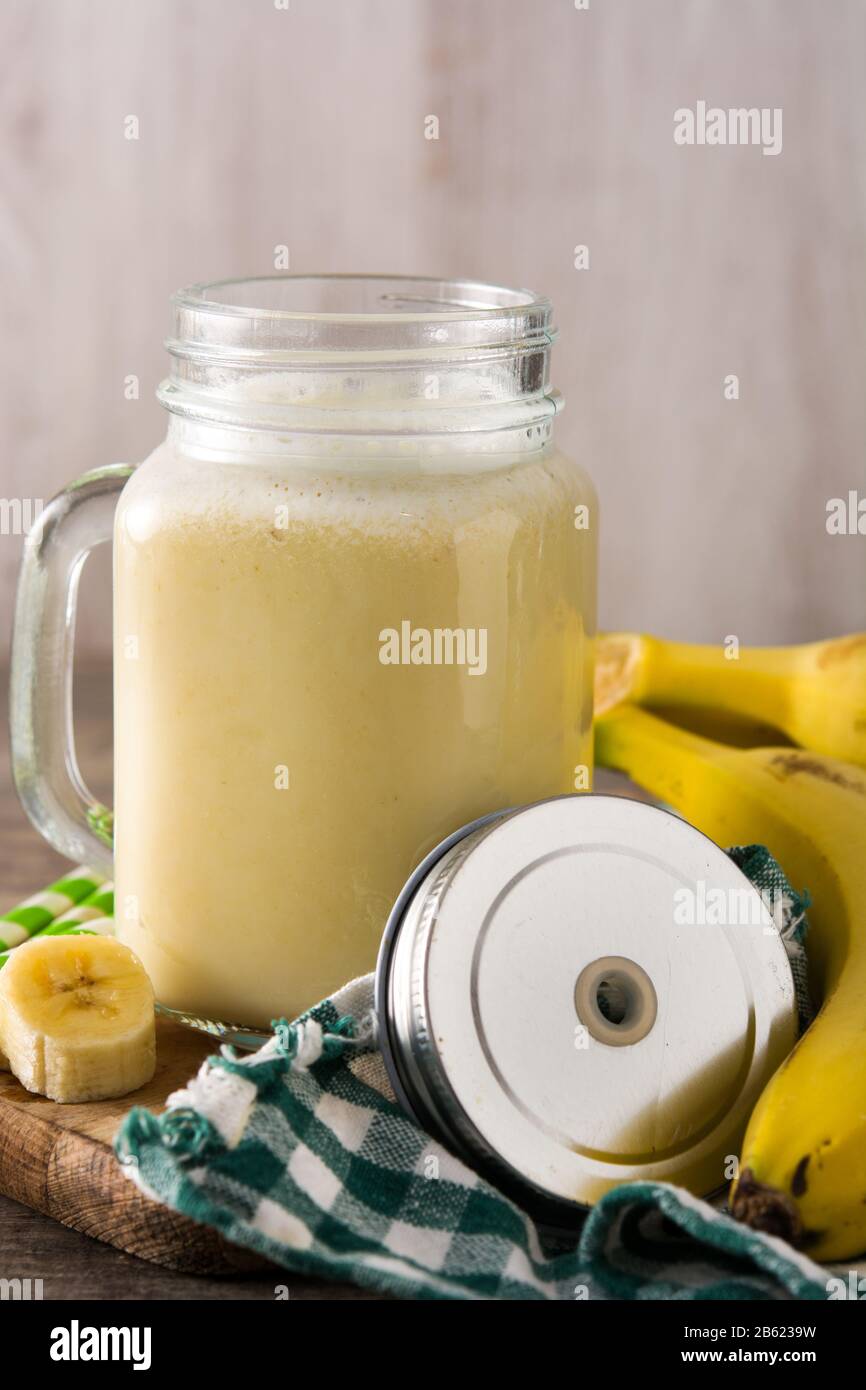Bananen-Smoothie im Mixbecher auf Holztisch Stockfoto