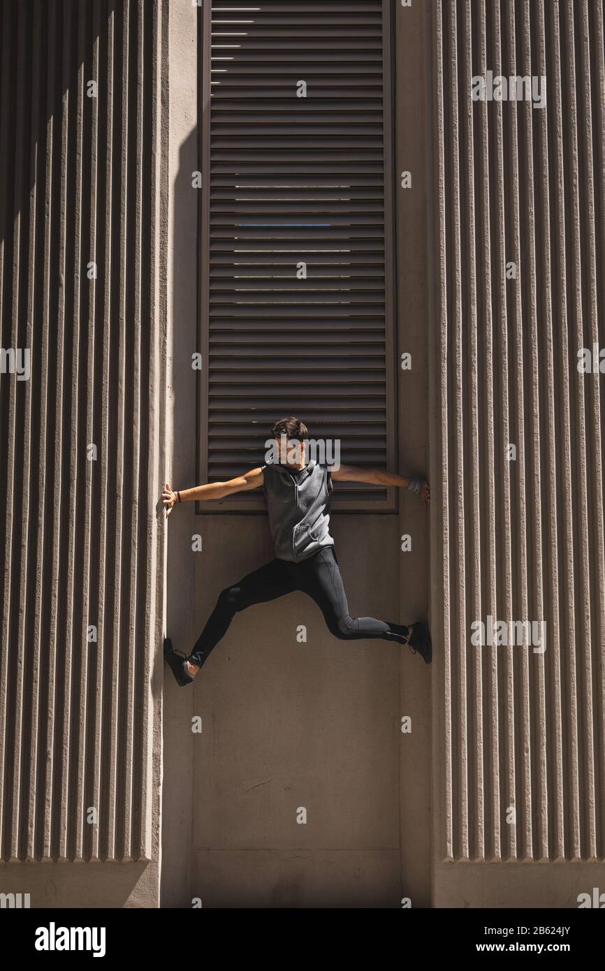 Kaukasischer Mann klettert am sonnigen Tag in das Gebäude Stockfoto