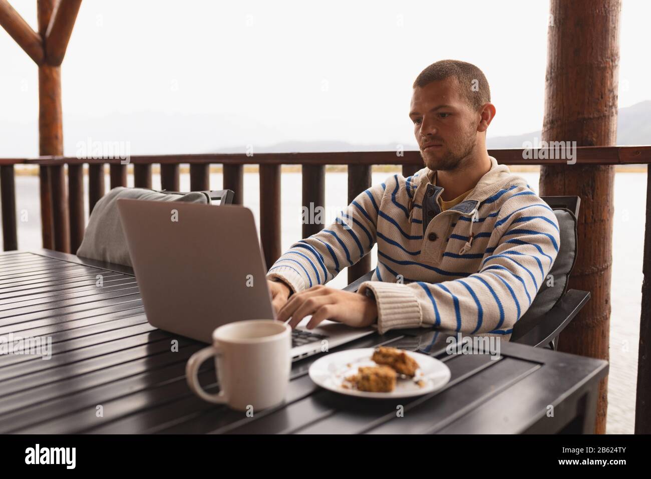 Kaukasischer Mann, der auf seinem Laptop auf seinem Balkon arbeitet Stockfoto