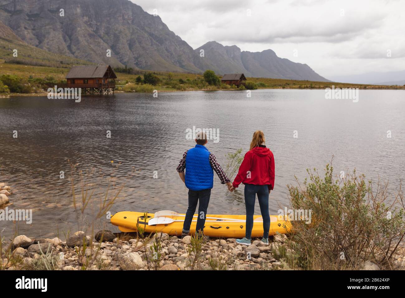 Kaukasische Paare genießen den Blick auf den See in der Nähe ihres Kajaks Stockfoto