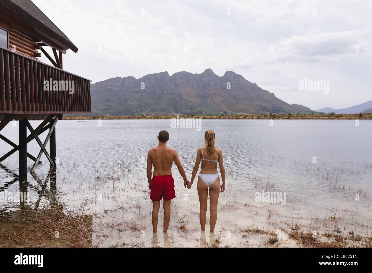 Kaukasisches Paar bereit, im See in der Nähe des Holzschuppens zu schwimmen Stockfoto
