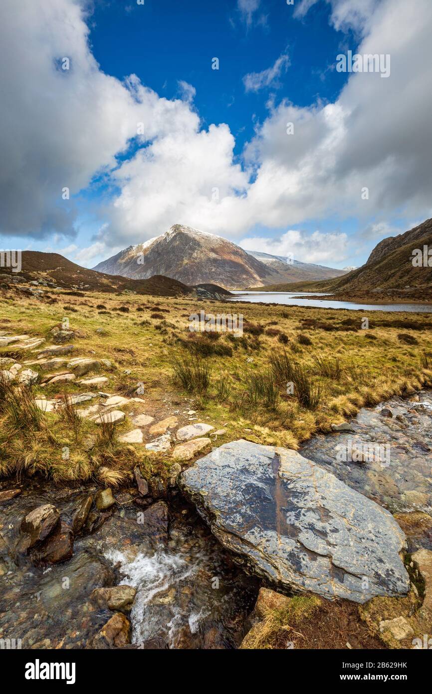 Stepping Stones über Schmelzwasser von schneebedecktem Glyder Fawr, das nach Llyn Idwal führt, mit Pen yr Ole Wen im Hintergrund, Snowdonia, Nordwales Stockfoto