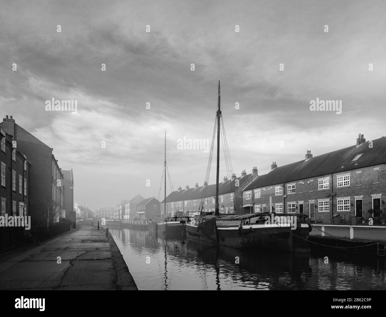 Restaurierte Lastkähne moorierten am beck (Kanal) an einem ruhigen, hellen Morgen im Frühjahr, der von Bürgerhäusern in Beverley, Yorkshire, Großbritannien, flankiert wurde. Stockfoto