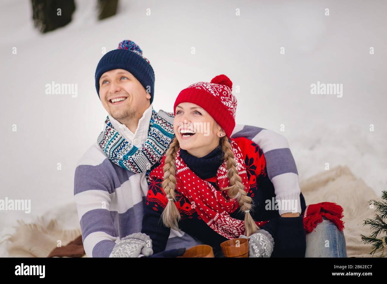 Junge Paare in warmen Pullovern im Winter blicken auf den Himmel. Stockfoto