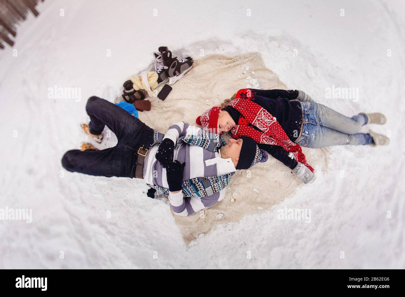 Liebevolles junges Paar liegt auf Decke im Winterpark. Stockfoto