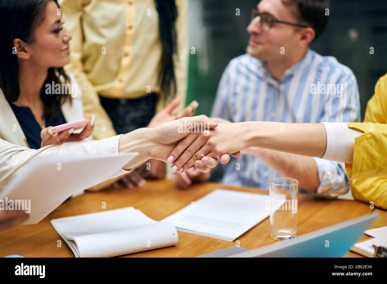 Junge Frauen begrüßen sich bei der Sitzung. Hallo. Guten Morgen, schön, Sie kennenzulernen, Nahaufnahme eines geschnittenen Fotos, Leute reden im verschwommenen Hintergrund Stockfoto