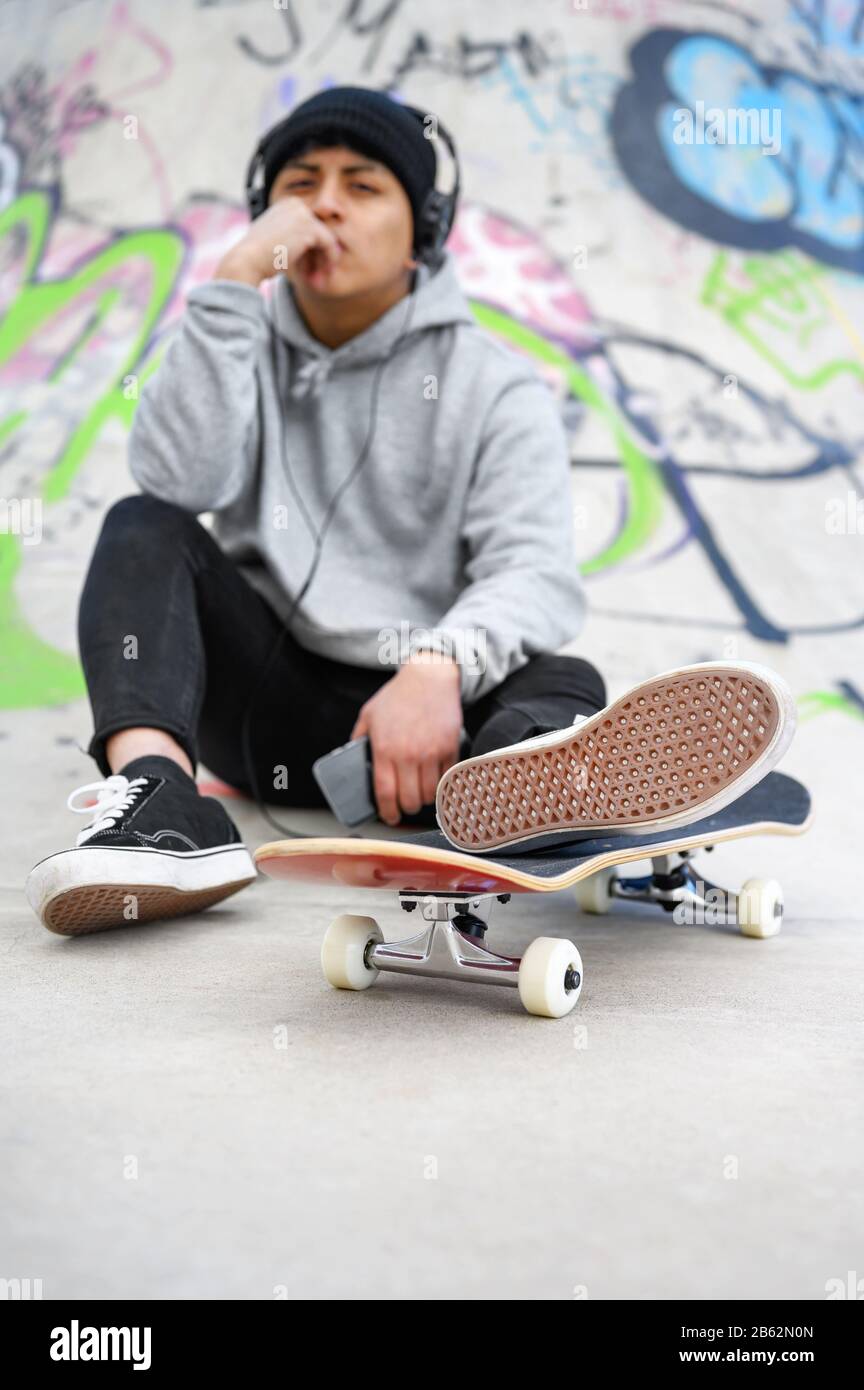Junger lateinischer Skater-Mann posiert mit Skateboard im Skatepark. Stockfoto