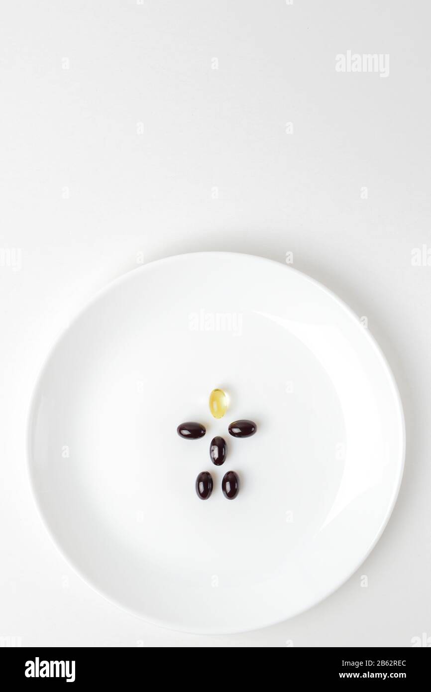 Astaxanthin- und Fischölpillen bilden auf der weißen Platte eine menschliche Form. Kopiere Platz oben. Stockfoto