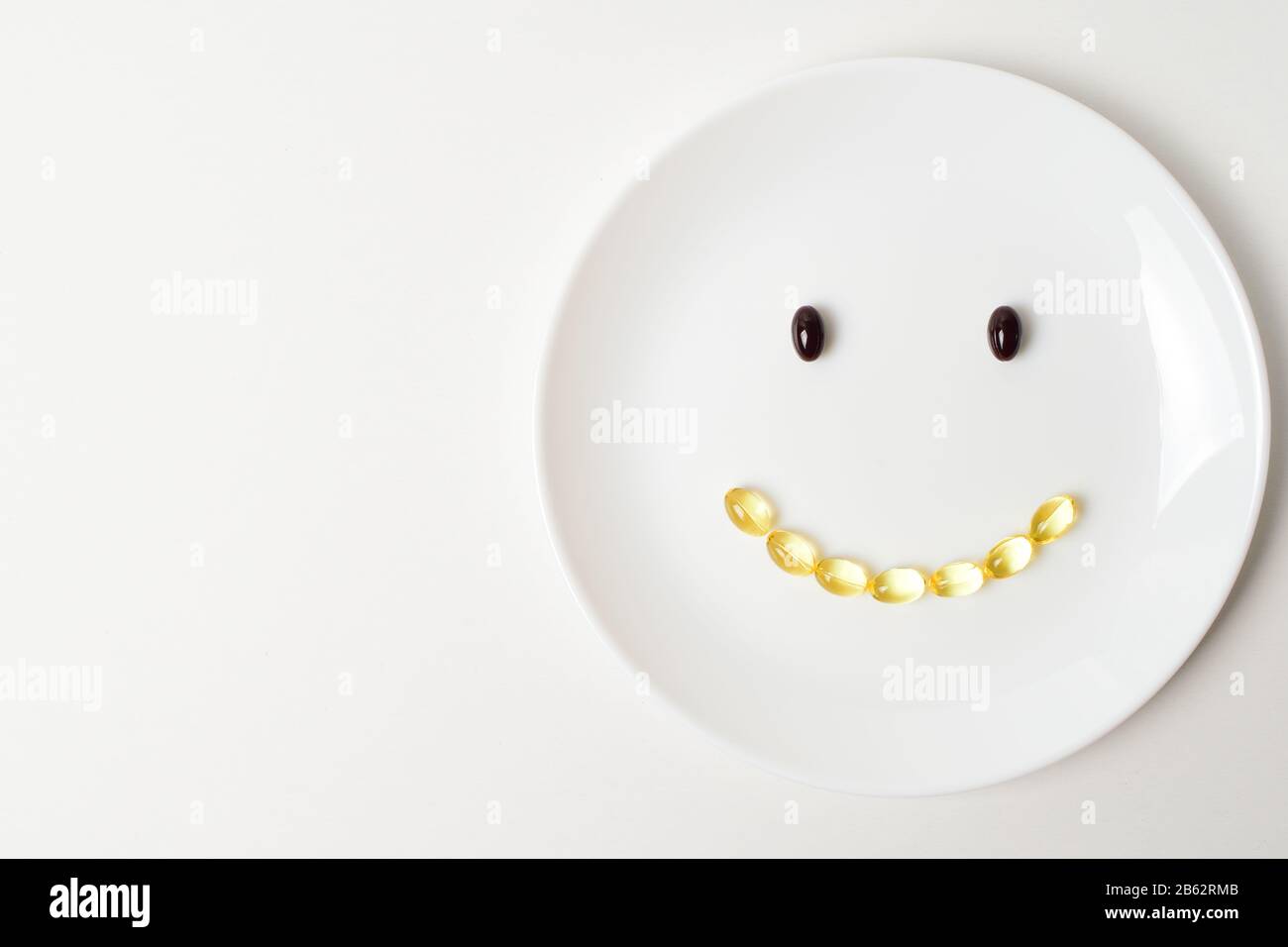 Astaxanthin und Fischöl bilden ein Lächeln auf einem weißen Teller. Kopieren Sie den Speicherplatz auf der linken Seite. Stockfoto