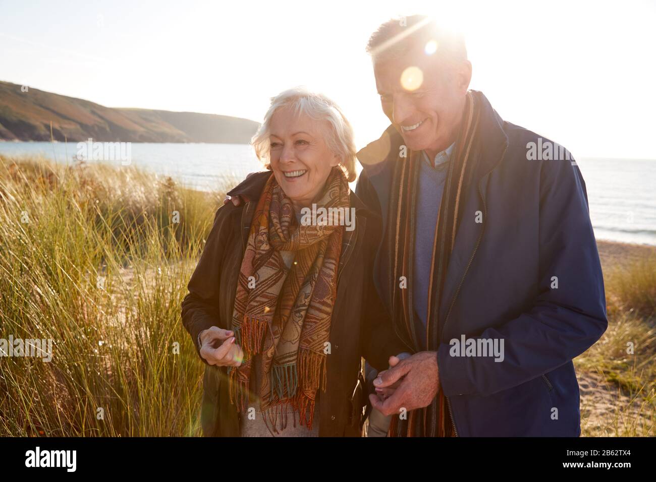 Liebevolles Aktives Älteres Paar Arm Im Arm, Das Durch Sanddünen Geht Stockfoto