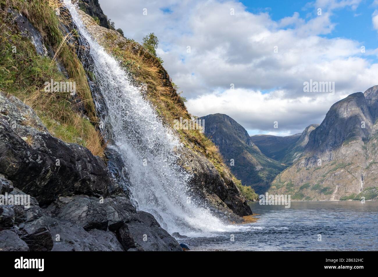 Wasserfall, der in den norwegischen Fjord Aurlandsfjord fällt. Nahaufnahme des hellen weißen Wassers auf den wilden Bergen in der Natur Norwegens. Sonniger Reisetag. Stockfoto