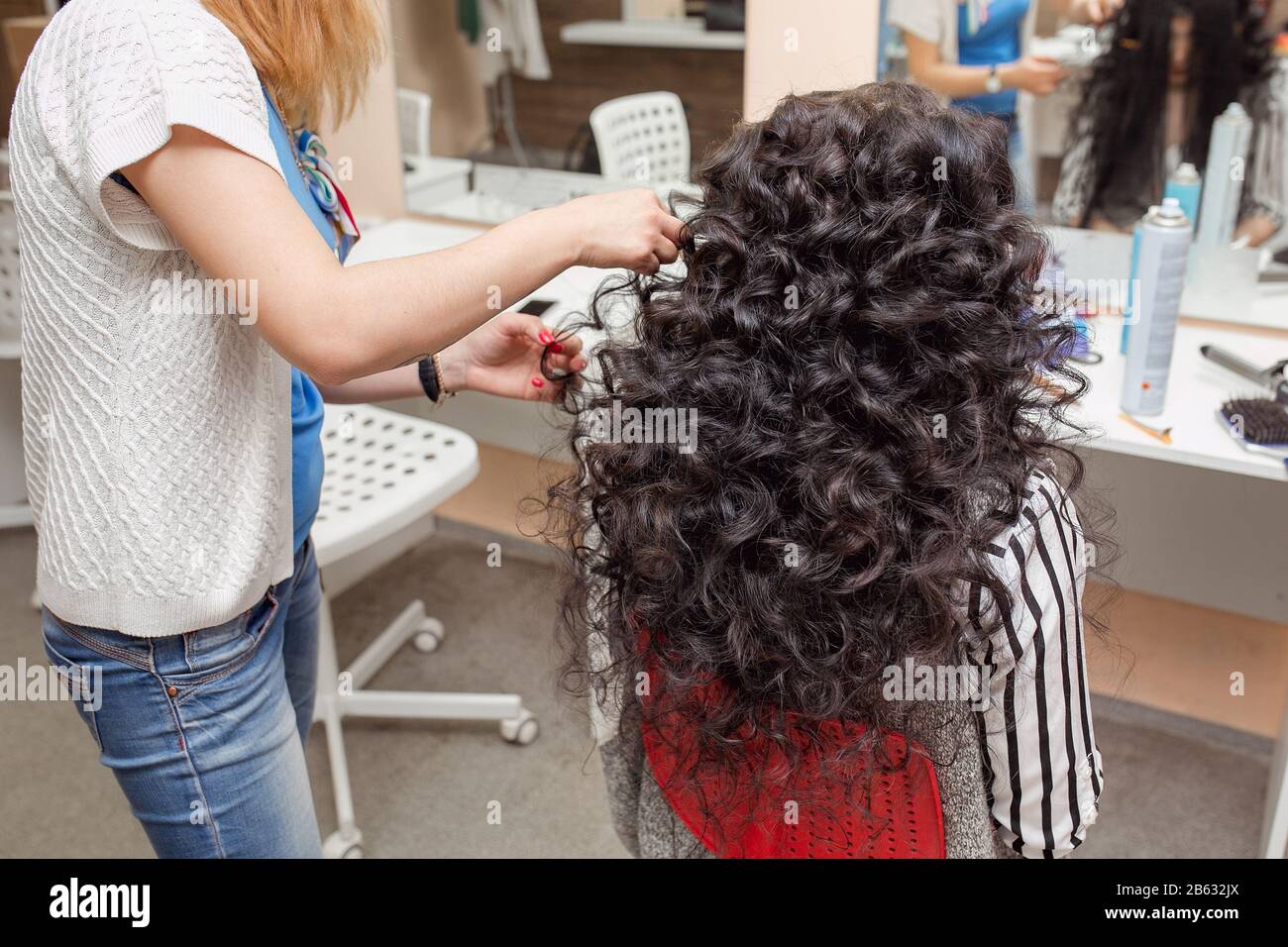 Barber Hand hält die Brunette-Locken im Friseursalon Stockfoto