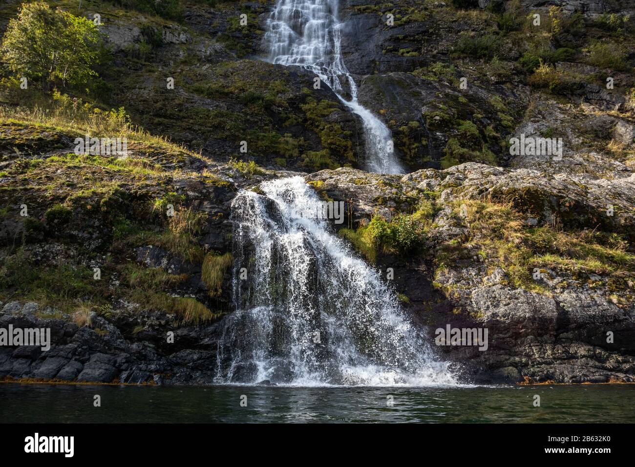 Wasserfall, der in den norwegischen Fjord Aurlandsfjord fällt. Nahaufnahme des hellen weißen Wassers auf den wilden Bergen in der Natur Norwegens. Sonniger Reisetag. Stockfoto