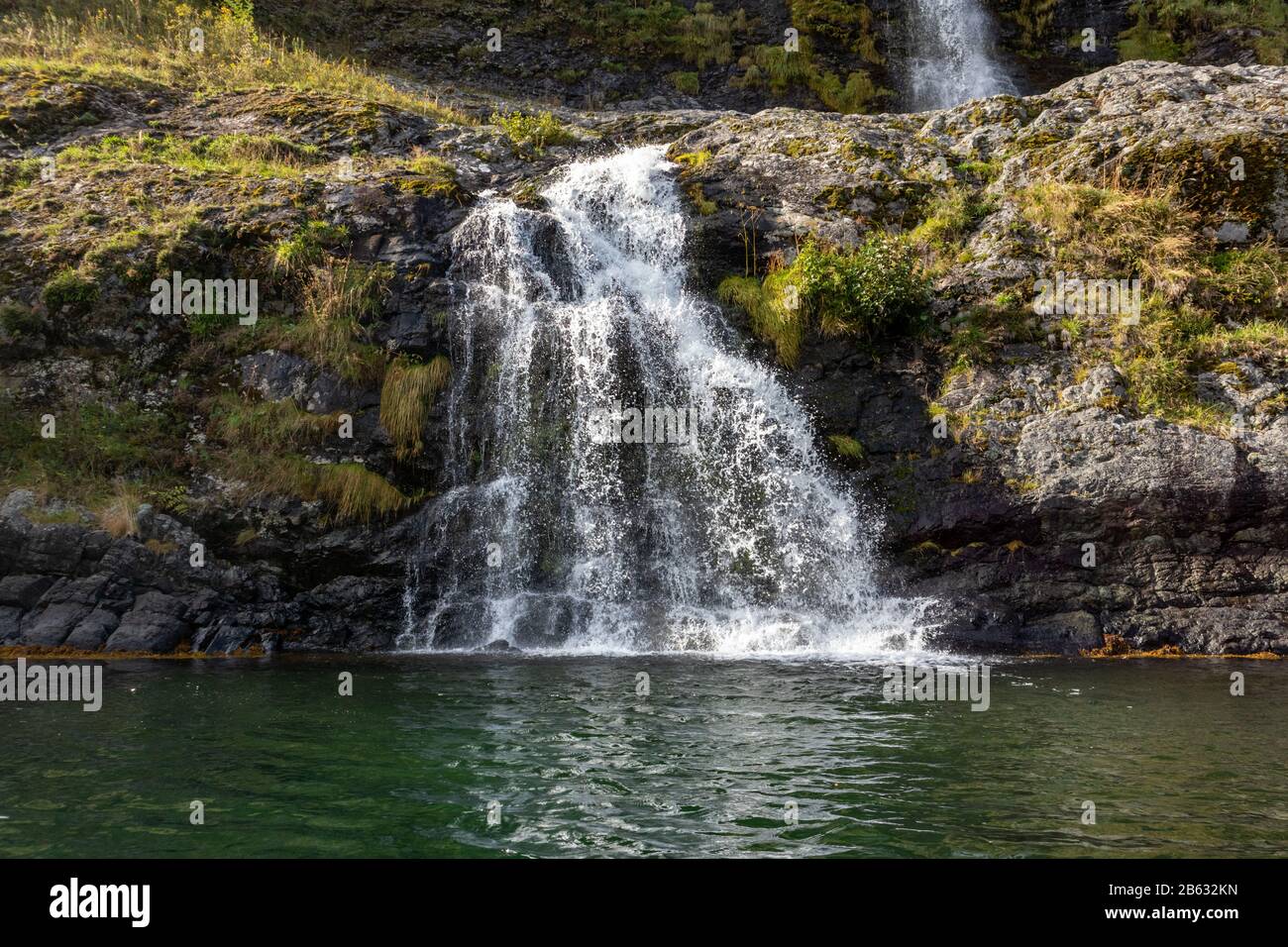 Wasserfall, der in den norwegischen Fjord Aurlandsfjord fällt. Nahaufnahme des hellen weißen Wassers auf den wilden Bergen in der Natur Norwegens. Sonniger Reisetag. Stockfoto