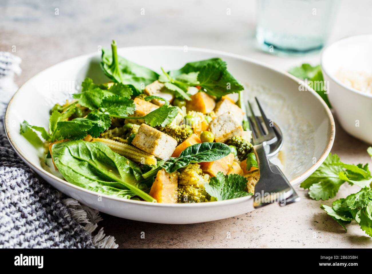 Veganer grüner Curry mit Tofu, Süßkartoffel, Mais und Spinat. Gesundes veganes Lebensmittelkonzept. Stockfoto