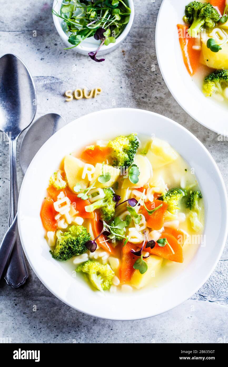 Gesunde Kinder Alphabet Suppe mit Gemüse und Nudelbuchstaben in weißen Platten. Babynahrungskonzept. Stockfoto