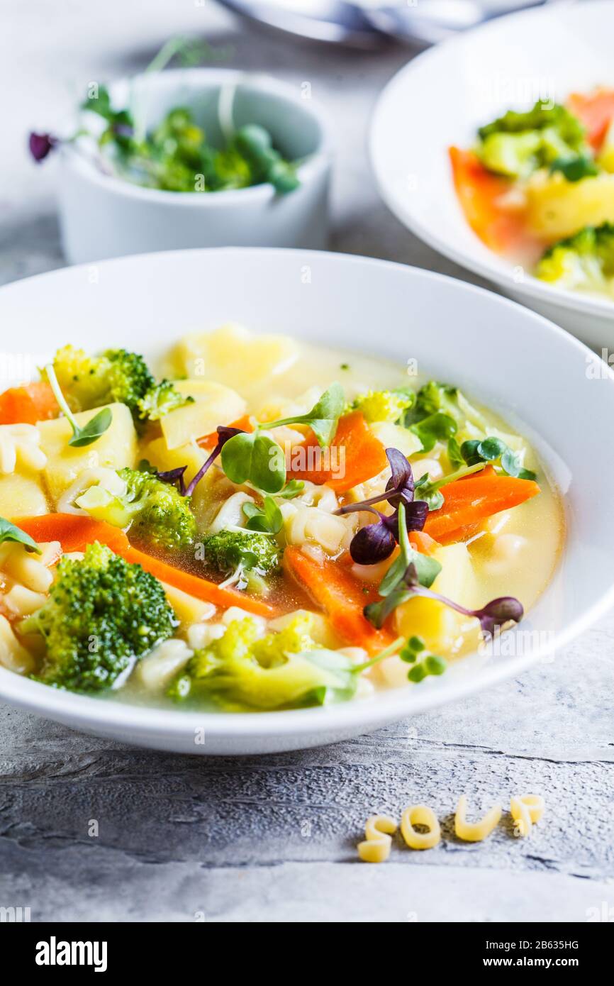 Gesunde Kinder Alphabet Suppe mit Gemüse und Nudelbuchstaben in weißen Platten. Babynahrungskonzept. Stockfoto