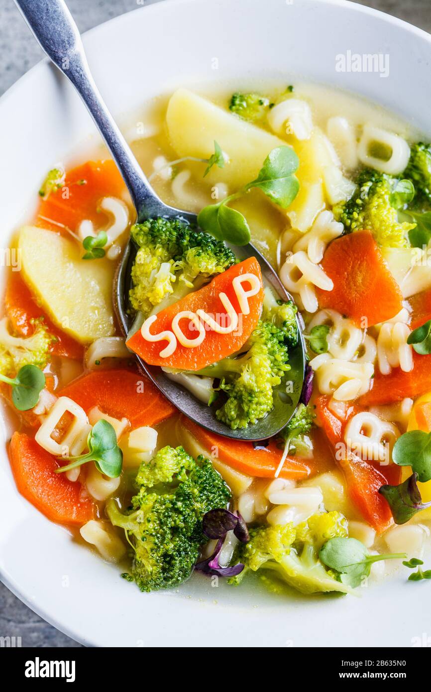 Gesunde Kinder Alphabet Suppe mit Gemüse und Nudelbuchstaben in weißen Platten. Babynahrungskonzept. Stockfoto