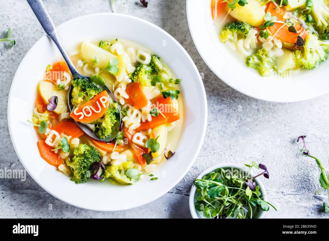 Gesunde Kinder Alphabet Suppe mit Gemüse und Nudelbuchstaben in weißen Platten. Babynahrungskonzept. Stockfoto