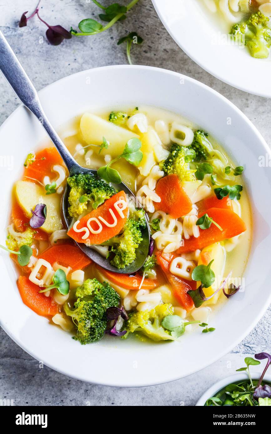Gesunde Kinder Alphabet Suppe mit Gemüse und Nudelbuchstaben in weißen Platten. Babynahrungskonzept. Stockfoto