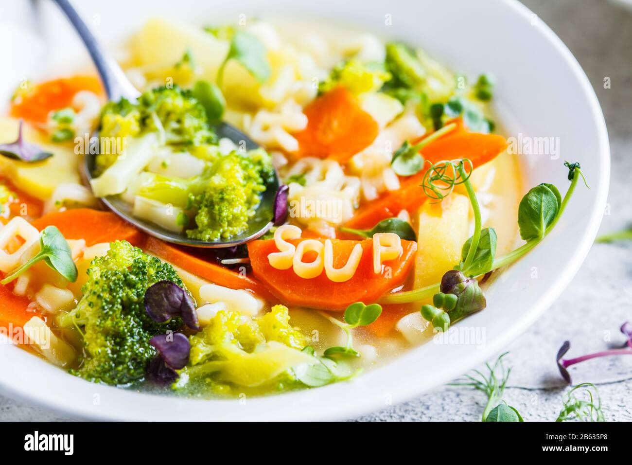 Gesunde Kinder Alphabet Suppe mit Gemüse und Nudelbuchstaben in weißen Platten. Babynahrungskonzept. Stockfoto