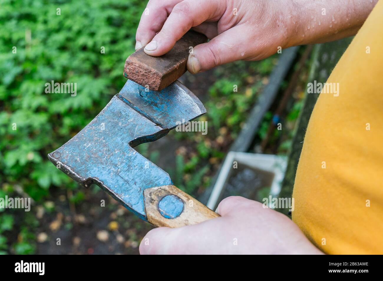 Ein Mann schärft eine Axt mit einem Schleifstein Stockfotografie - Alamy