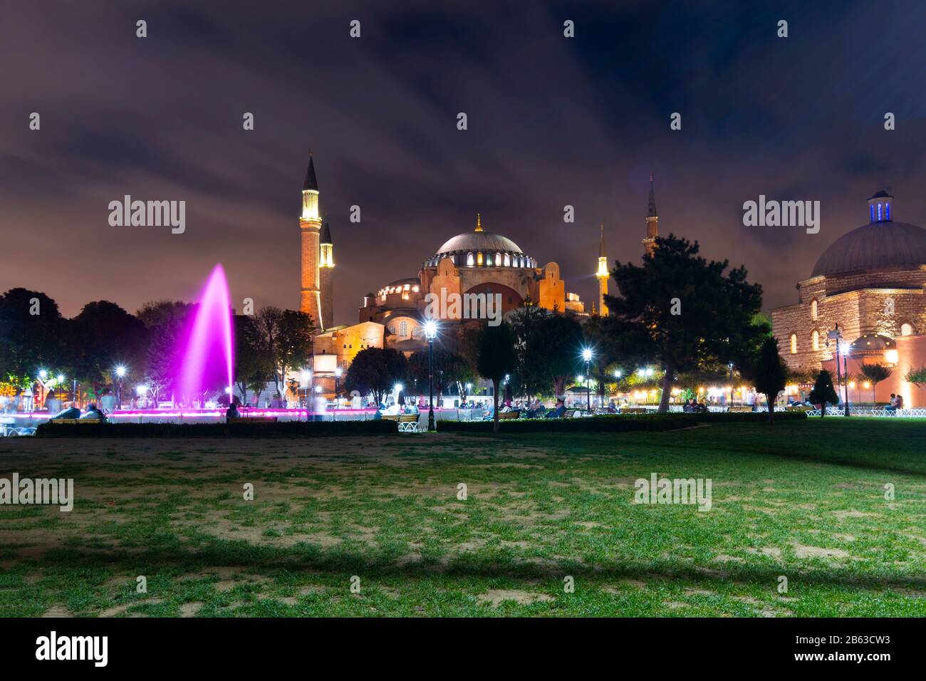 Die Hagia Sophia-Moschee und das Museum mit dem bunten Wasserbrunnen und dem Park, der am Abend auf dem Sultanahmet-Platz in Istanbul, Türkei, beleuchtet wird. Stockfoto