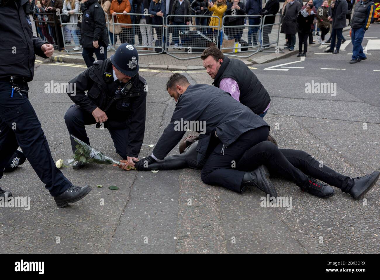 Pro-Demokratie-Demonstranten mit einer Gruppe Freier Südkamerun werden von Polizisten der Metropolitan angegangen, nachdem sie während des von der Königin geführten Dienstes des Commonwealth Day außerhalb der Westminster Abbey von hinter Hindernissen gestürmt wurden und Mitglieder der britischen Königsfamilie sowie Botschafter und Würdenträger des Commonwealth eingeschlossen haben. Sie halten am 9. März 2020 in London, England, Plakate mit den Worten "Freier Präsident Ayuktabe Julius" (ein ambazonischer Separatistenführer) und "Gerechtigkeit für Babanki" (in Bezug auf die Vorwürfe von Soldatenmorden an Dorfbewohnern). Auf dieser, ihre letzte königliche Pflicht, bevor sie sich für Stockfoto