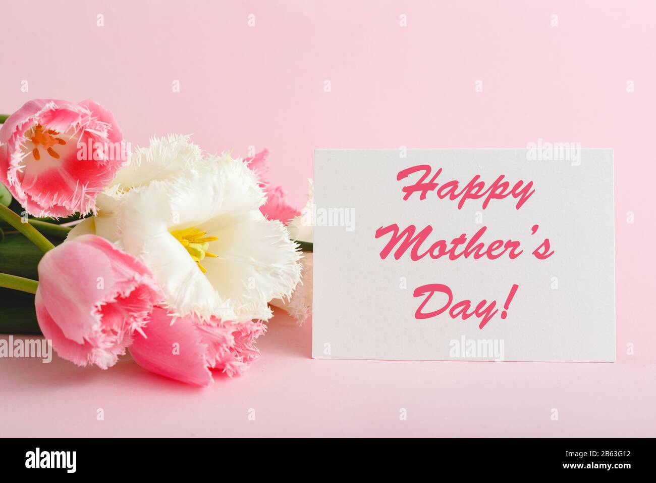Happy Mothers Day Text auf Geschenkkarte in Blumenstrauß auf pinkfarbenem Hintergrund. Grußkarte für Mama. Blumenlieferung, Glückwunschkarte in Blumen für Stockfoto