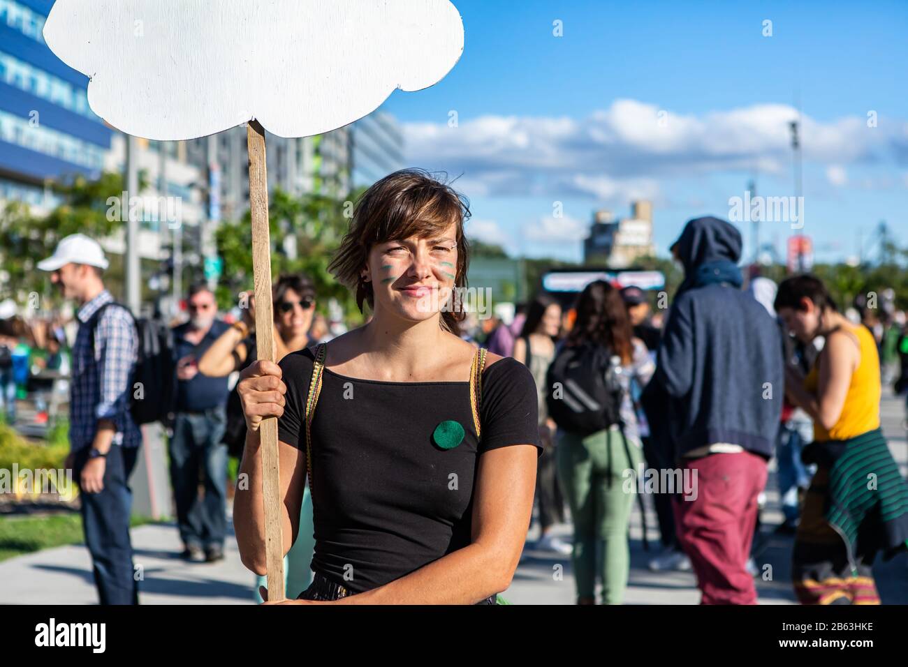 Ein Nahporträt einer blonden Frau, die während eines Protests für Klima und Umwelt ein selbstgefertigtes Schild in Wolkenform mit leerem Kopierraum hält Stockfoto