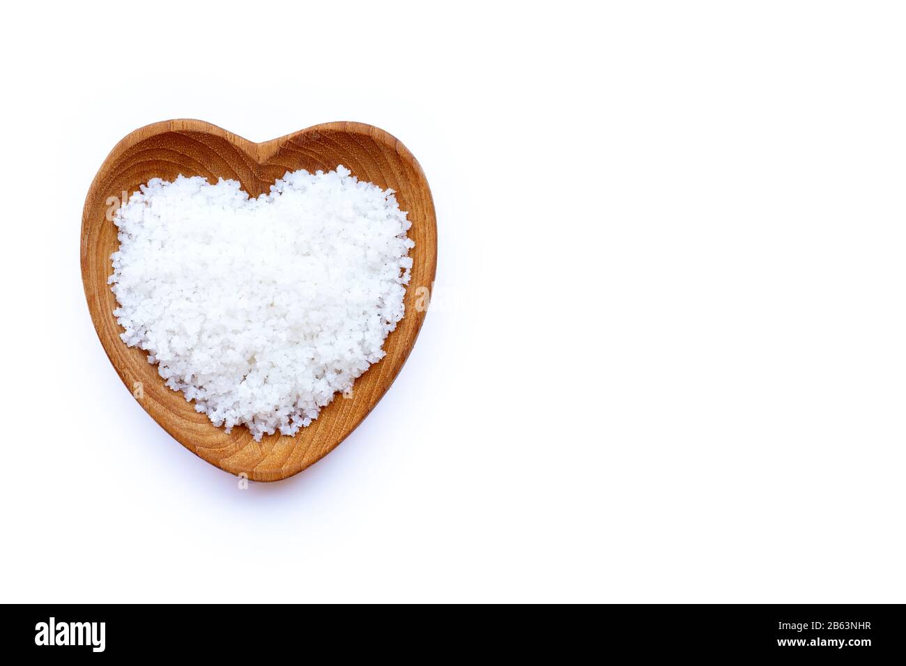 Salzblume in herzförmiger Holzschale auf weißem Grund. Stockfoto