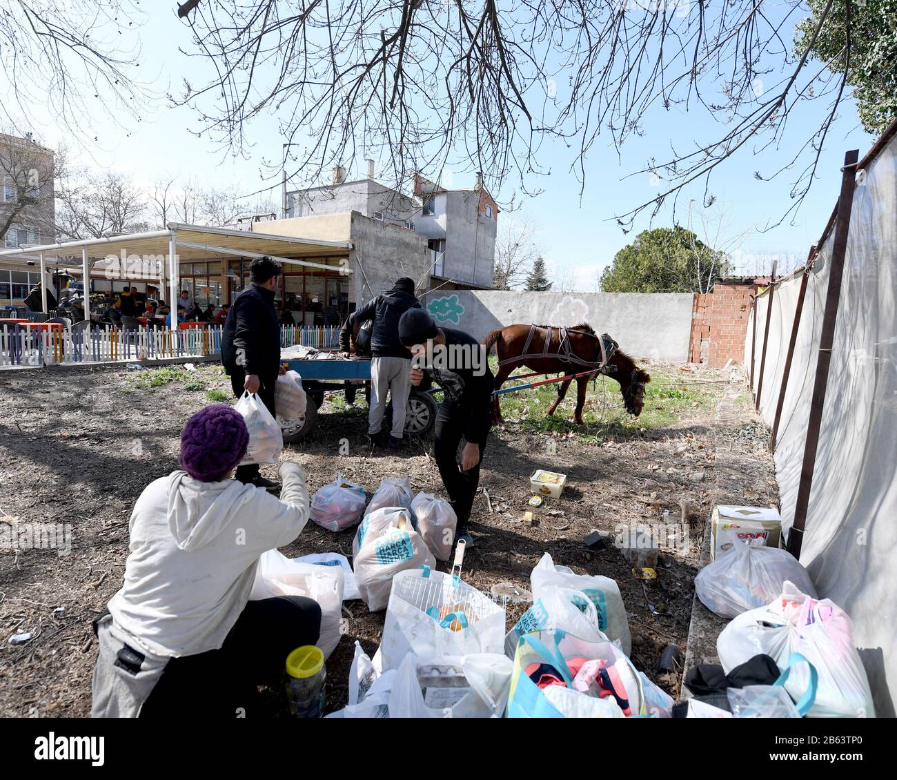 Eine Flüchtlingsfamilie packt ihre zerleppten Gegenstände auf einen Pferdewagen.Die humanitäre Krise in Edrine, der Türkei an der Grenze zu Griechenland, befindet sich derzeit in einem Patt, in dem etwa 6.000 Flüchtlinge in einem gezettelten Lager am Grenzübergangsort Pazakule verbleiben. Der lokale Supermarkt im nahe gelegenen Karaagac macht guten Handel mit der Roma-Zigeunergemeinschaft, die Pferdetaxifahrten für die 1 km lange Fahrt in die Stadt anbietet. Zahlreiche Pop-up-Stände entstehen als Bargeld der Einheimischen für diese neue gefundene Wirtschaft. Die griechische Grenzkontrolle reißt die meisten Tage noch Gas, aber die Zahl der versuchten Übergänge ist geringer. Neue Arriva Stockfoto