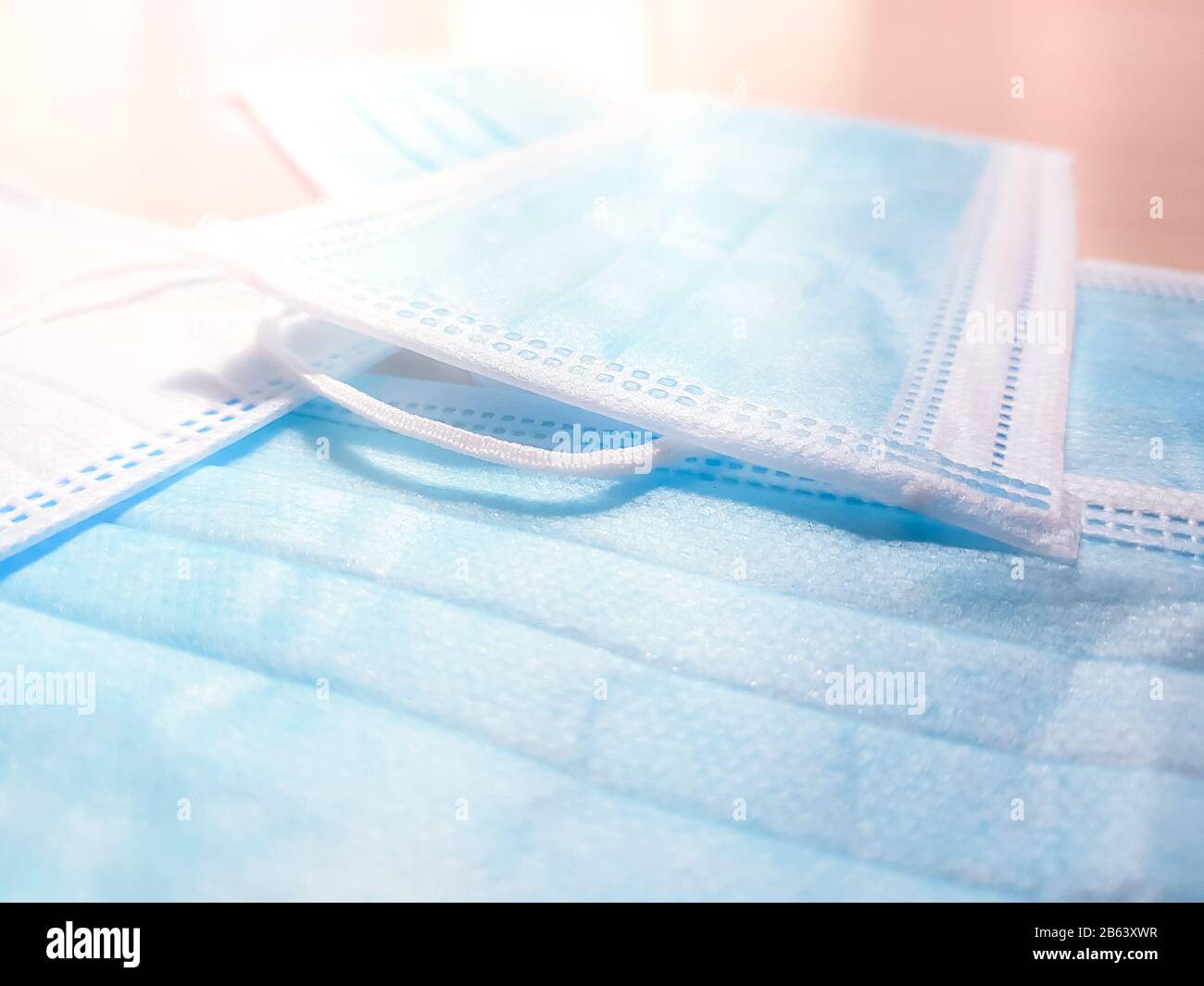 Blauweiße medizinische Gesichtsmasken auf dem Tisch. Seitenansicht, Nahaufnahme. Stockfoto