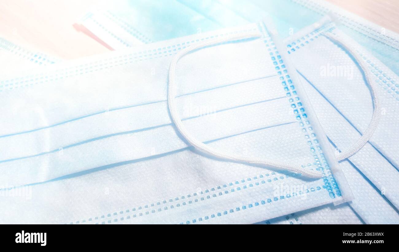 Blauweiße medizinische Gesichtsmasken auf dem Tisch. Seitenansicht, Nahaufnahme. Stockfoto