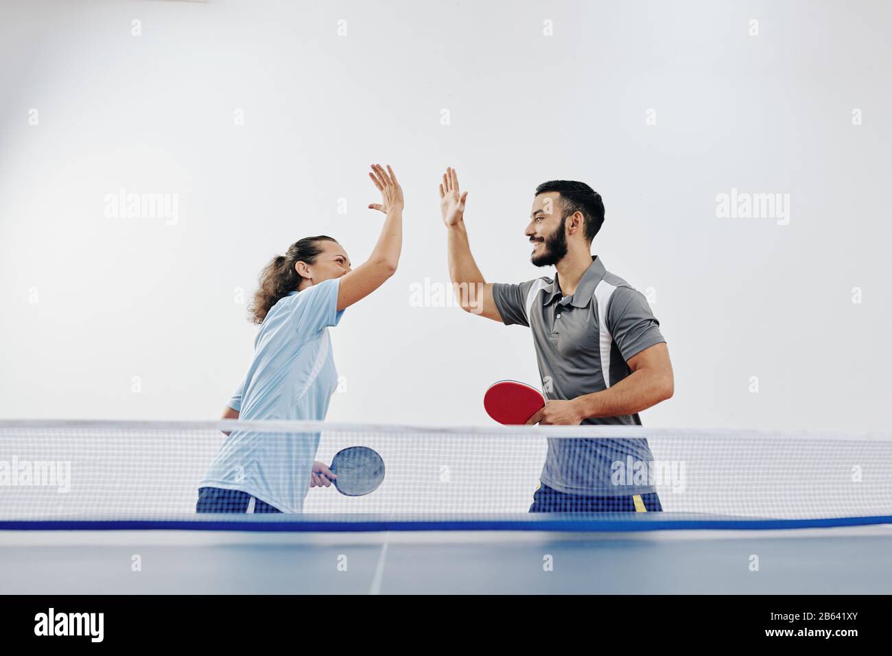 Glückliches Team von Tennisspielern, die sich nach dem Sieg im Wettkampf fünf hoch gaben Stockfoto