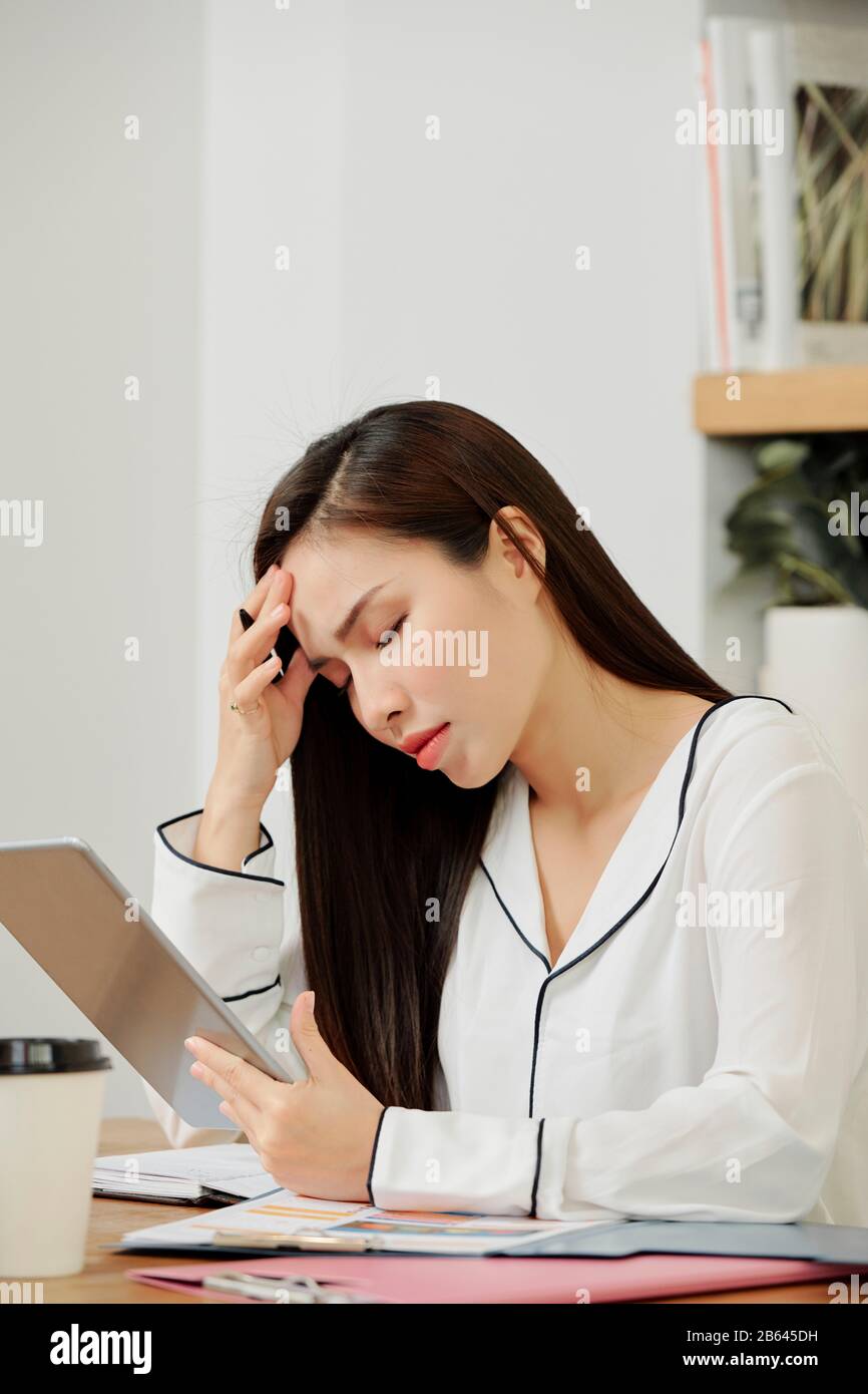 Betonte junge Managerin, die sich nach der Arbeit am Projekt den ganzen Tag über Kopfschmerzen bereitet Stockfoto