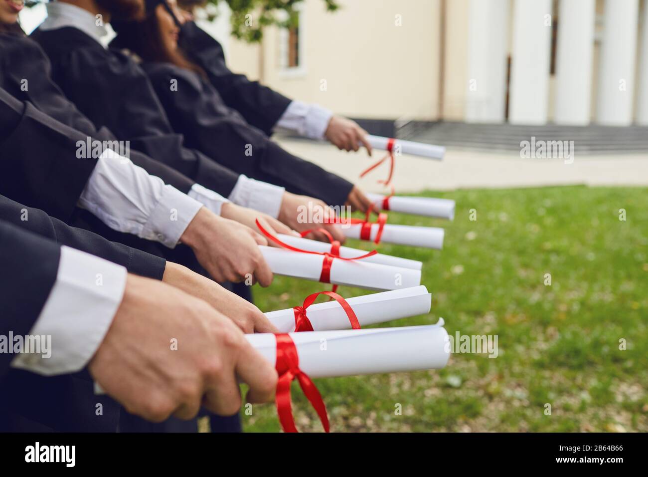 Scrollt Diplome in den Händen einer Gruppe von Absolventen. Stockfoto