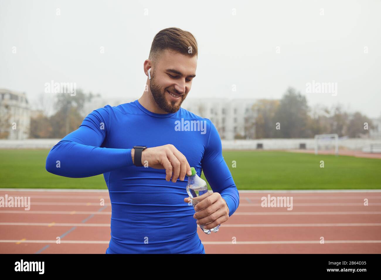 Sportlicher Mann mit einer Flasche Wasser im Training im Stadion. Stockfoto