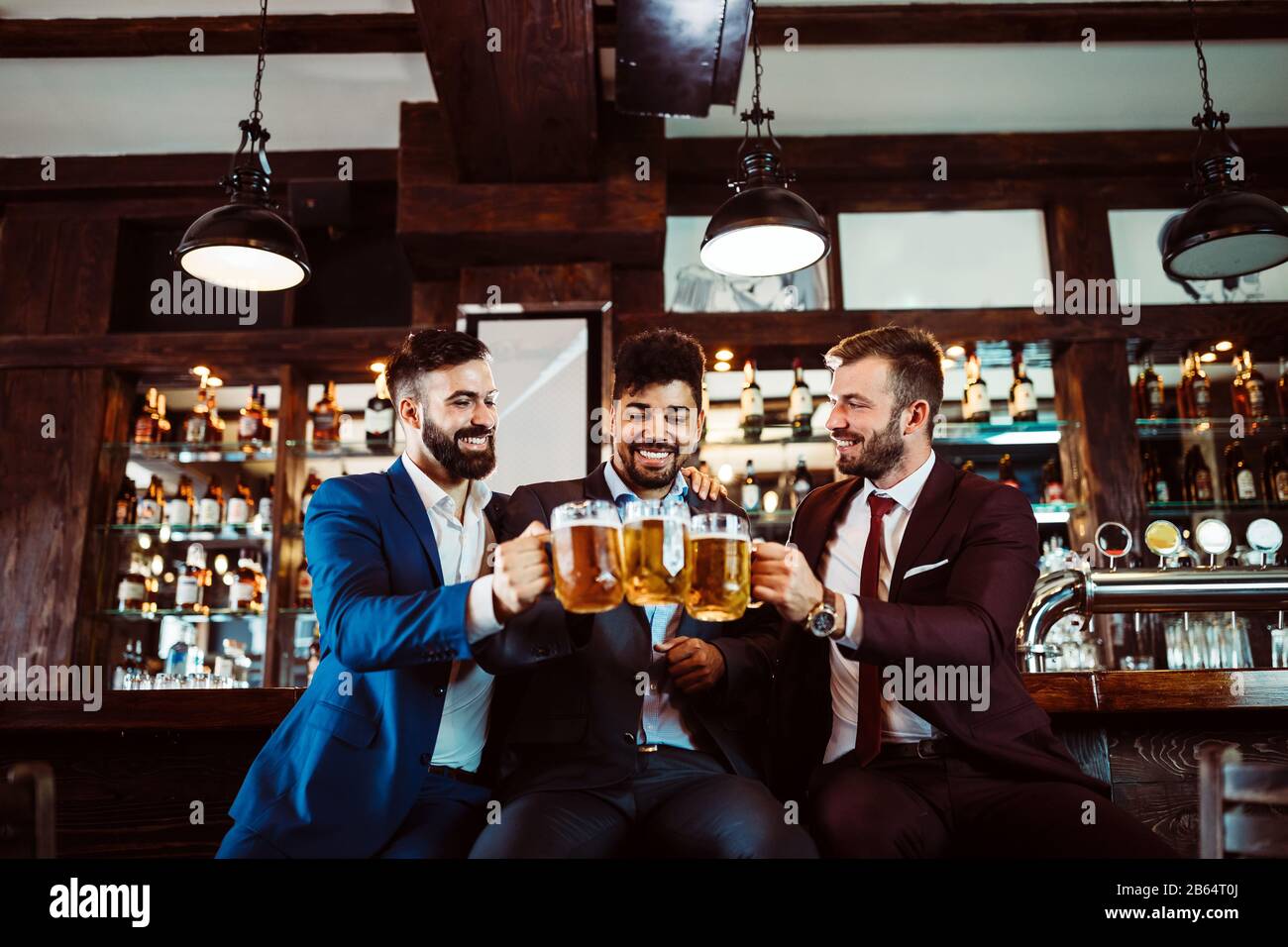 Menschen-, Freundschafts- und Festkonzept. Fröhliche Geschäftsleute, männliche Freunde, die Bier in der Kneipe trinken Stockfoto